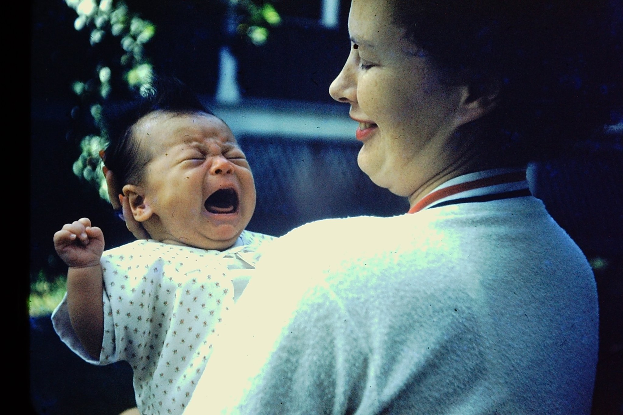 A photo of my mom hold a crying baby me in her arms.